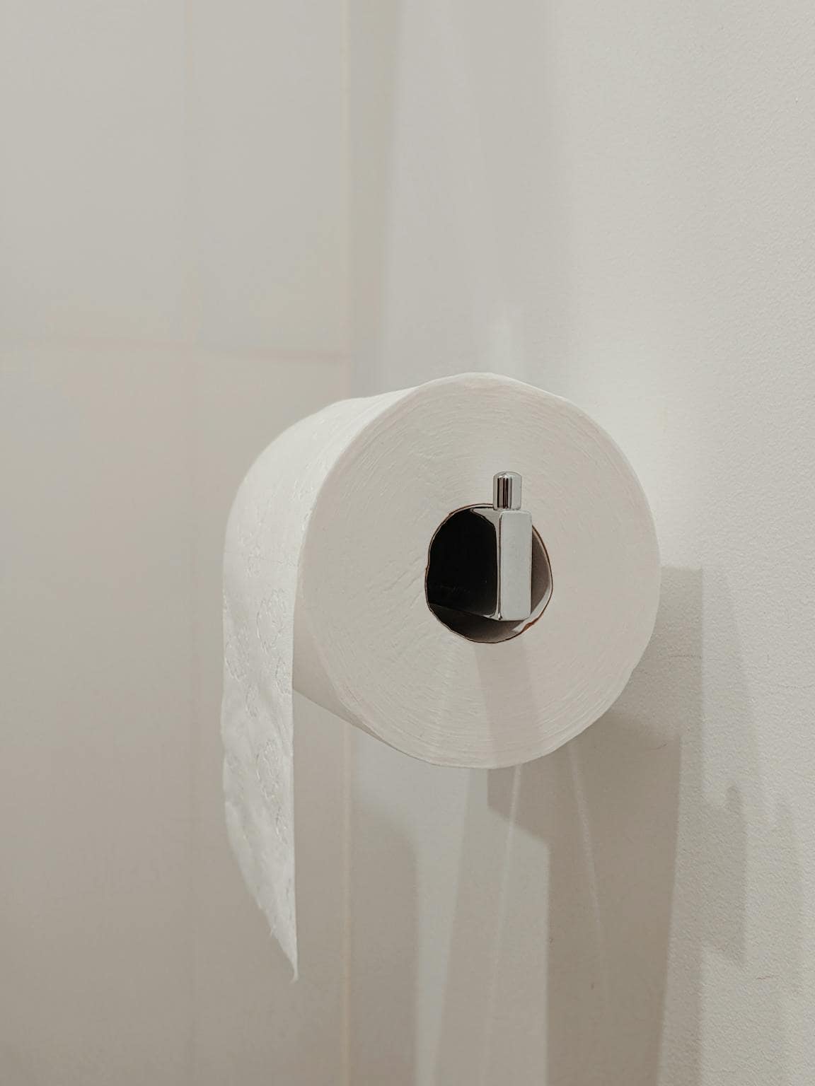 A simple and clean bathroom setting with a white toilet paper roll on a wall holder.